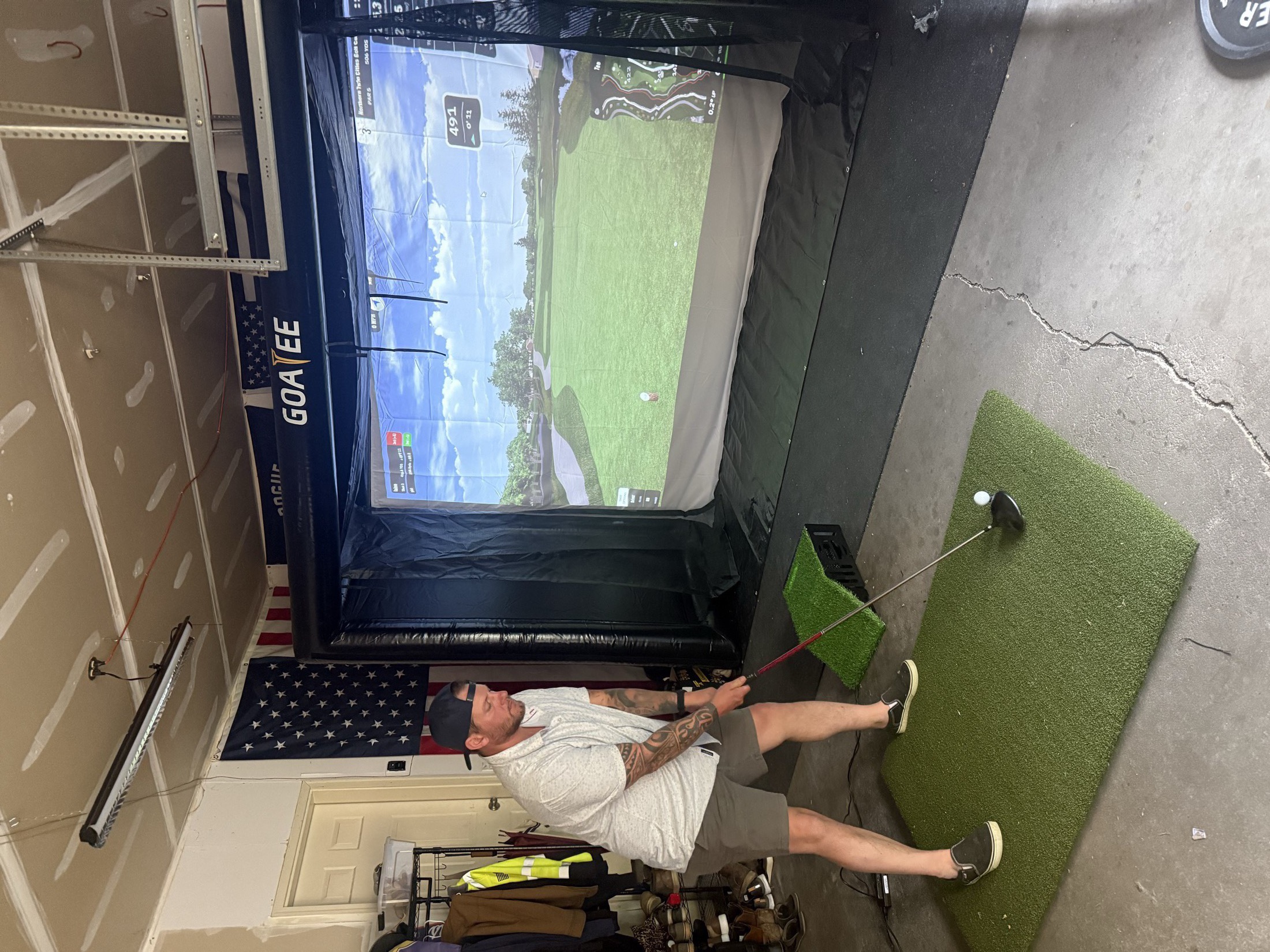 A guest mid-swing inside the Goatee inflatable simulator bay, ball tracked on the projected course